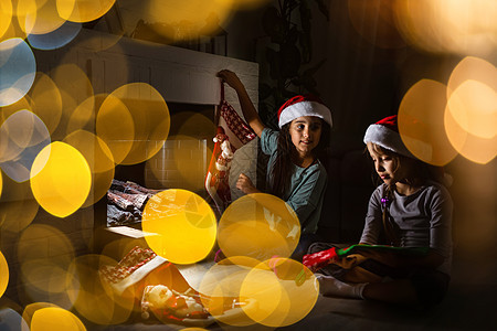 孩子们在庆祝圣诞节的温馨家庭里 在壁炉旁边开小礼物朋友们房子兄弟姐姐展示女孩场景房间蜡烛季节图片