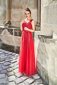 美丽的伴娘黑发女孩女士穿着优雅的全长红色雪纺伴娘礼服 带蕾丝 手捧花束 婚礼当天的欧洲老城区地点图片