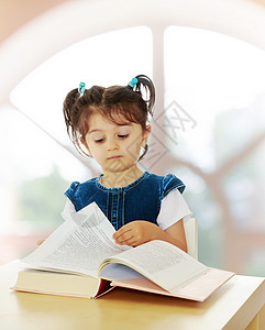 小女孩在桌子上看一本书教育拱形孩子快乐学校女孩知识女学生童年圆圈图片