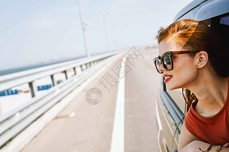 快乐的女人偷看 从汽车窗外旅行冒险的生活方式夫妻蓝色假期喜悦女性太阳窗户家庭驾驶潮人图片