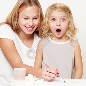 两个女孩在一张纸上涂油漆家庭刷子绘画工作室朋友们学习幼儿园艺术画家水彩图片