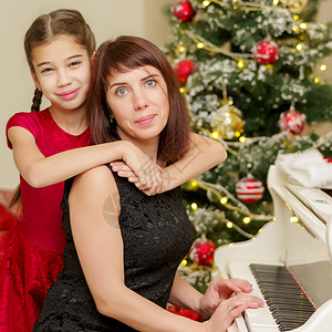 新年的妈妈和女儿 靠近白色钢琴的新年女性家庭钢琴家乐器母亲键盘婴儿父母女孩教育图片