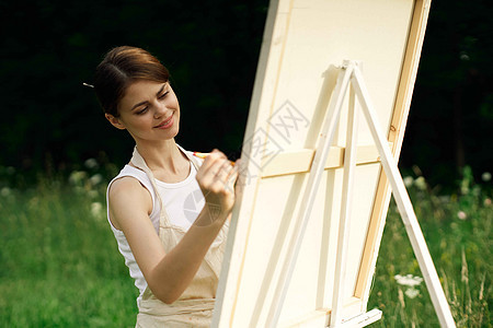 女艺术家在户外露台附近画一幅画森林女性绘画爱好画架闲暇女孩微笑艺术黑发图片