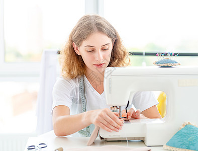 服装匠亲手缝纫新设计衣服机器桌子材料作坊工艺女孩测量剪裁纺织品图片