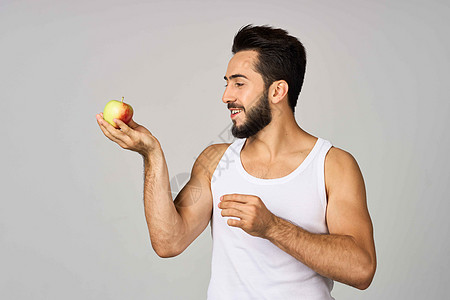 一个穿着白色T恤男子 新鲜水果苹果维他命工作室生活方式工作室男性健康黑发运动快乐爆炸饮食冒充成人图片