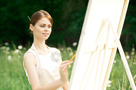 女艺术家在户外露台附近画一幅画森林学生女孩青少年画架画家艺术微笑工作绘画图片