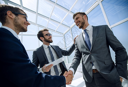 在现代办公室与商业伙伴进行握手团队微笑问候语会议交易男人合伙工作合作公司图片