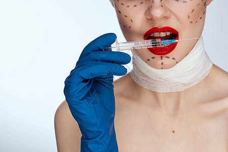 身穿蓝手套针筒的美女 手放在脸部的轮廓上 举起紧身衣塑料嘴唇手术程序诊所病人外科治疗化妆品医院图片