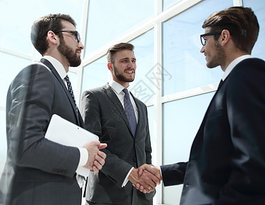 玻璃墙后面的商务伙伴握握手合作办公室商业协议男人反射微笑同事男性合伙图片