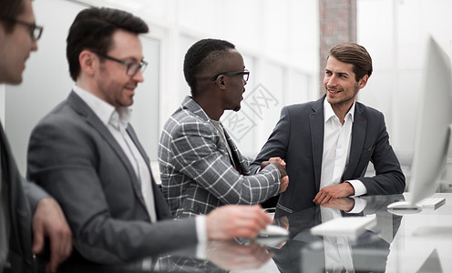 在办公桌与年轻的商业伙伴进行握手交流男人工作会议桌子职场招聘男性顾问讨论合作图片