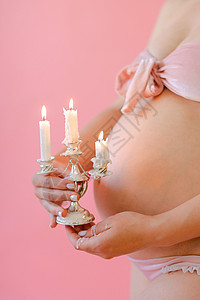 穿着内裤的孕妇紧紧闭肚子并保持蜡烛图片