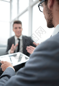 商务人士手中的平板电脑 男人在背景测试上讲话员工人士会议手势商务桌子技术合伙管理人员图片