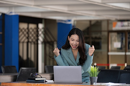 美丽的亚洲女人用笔记本电脑庆祝 成功的快乐姿势 电子商务 大学教育 互联网技术或创业小企业概念女士成就胜利喜悦成人管理人员企业家图片