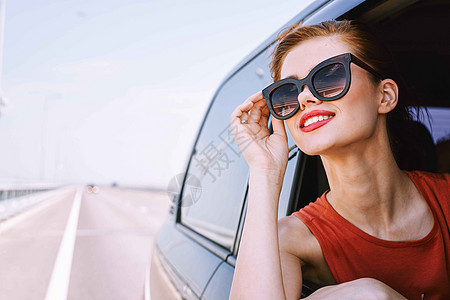 一个女人开车在路上 望着窗外的一辆车乐趣家庭窗户旅行晴天太阳潮人太阳镜假期车辆图片