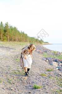年轻金发女郎在沙滩上散步 穿着夏衣图片