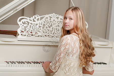 一个十几岁的女孩在弹白色大钢琴钢琴家仪器学校训练青少年闲暇学习童年旋律乐趣图片