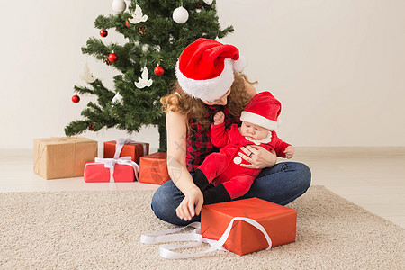 家庭 童年和圣诞节概念  快乐母亲和穿着圣诞老人衣服的可爱婴儿的画像烛台传统帽子风格孩子房间女性假期礼物男生图片