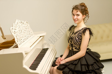 一个十几岁的女孩在弹白色大钢琴键盘乐器闲暇童年器官艺术家钢琴家钥匙学习教育图片