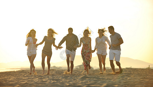 快乐的年轻人团体在海滩上玩得开心女士乐趣跑步微笑运动活力团队生活娱乐季节图片