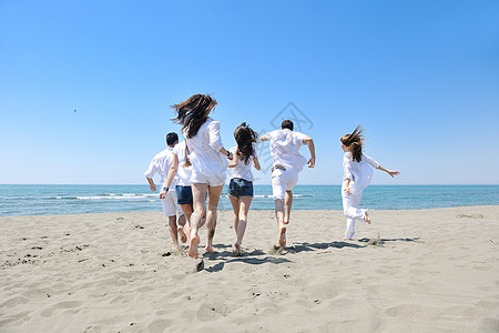 快乐的年轻人团体在海滩上玩得开心女性活力男人女士乐趣天空季节跑步喜悦团队图片