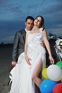 刚结婚的夫妇在海滩上骑白色摩托车旅行支撑婚姻男人乐趣女士蜜月新娘裙子夫妻图片