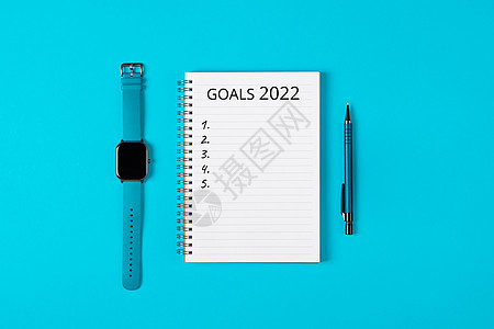 2022年目标概念旗帜 笔记本 铅笔和蓝背景的手表图片
