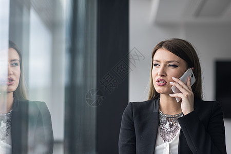 商业女商务人士在现代建筑中站着 接近有电话的窗口技术购物商务女士成功管理人员女孩微笑互联网快乐图片