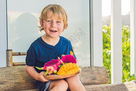 龙果和芒果 在男孩的手中异国温泉亚麻香蕉木板沙拉叶子水果果汁饮食图片