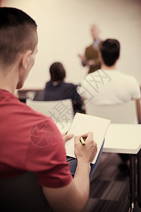 男学生在课堂做笔记桌子笔记本团队测试成人男性演讲学习会议训练图片