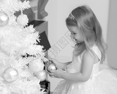 有个小女孩在装饰圣诞树呢女孩针叶装饰品风格装潢礼物假期蜡烛庆典幸福图片