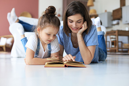 母亲和小女儿一起阅读一本书 躺在客厅的地板上的书女孩房间评书休息幸福地毯生活枕头地面家庭图片
