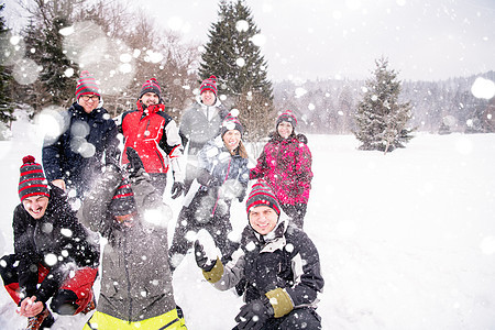 一群年轻人向天空中扔雪雪团体女士建筑树木雪花旅行爬坡朋友们男人团队图片