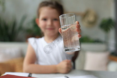 快乐的小女孩提供玻璃上的晶体矿泉水 小孩子建议每天用干净的水瓶来饮用娱乐头发口渴女性饮料房子场景幸福女孩治疗图片