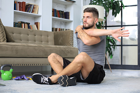英俊的男人在家里做伸展运动 健康生活的概念 笑声笔记本闲暇房子肌肉俯卧撑身体追求爱好训练地面图片