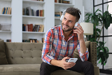 有吸引力的年轻人在家里沙发上放松 并使用手机在社会网中做菜人士成人商业工作电话微笑互联网男人技术男性图片