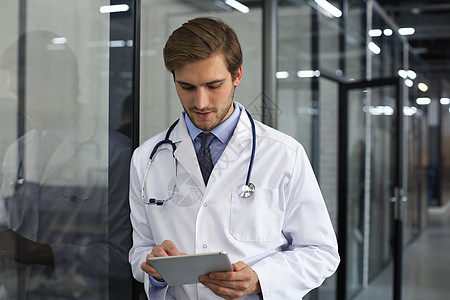 医生身穿实验室大衣和听诊器站在医院走廊的肖像窗户诊所科学服务领带管理人员成人研究医疗员工图片