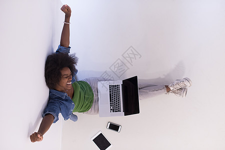 坐在有笔记本电脑最高视图的地板上的非裔美国妇女微笑爆炸闲暇地面互联网成人工作女孩女士技术图片
