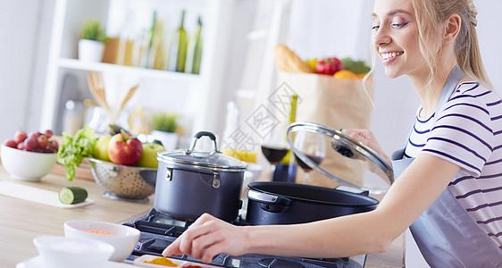 美丽的年轻女子在家厨房做饭 在厨房做饭围裙房子食物盘子牛奶烘烤食谱管家玻璃餐巾图片