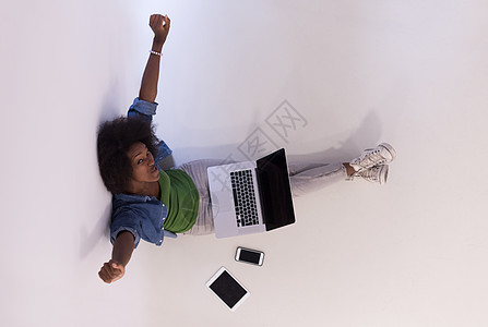 坐在有笔记本电脑最高视图的地板上的非裔美国妇女女孩成人幸福爆炸学生闲暇女士地面互联网微笑图片