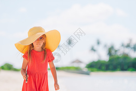 暑假时在沙滩上戴帽子的可爱小女孩海洋乐趣幸福旅游快乐喜悦微笑支撑旅行海岸图片