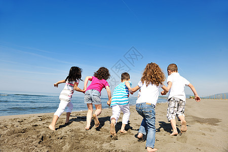 快乐的年轻人团体在海滩上玩得开心朋友们行动喜悦女性乐趣团队跑步假期娱乐活力图片