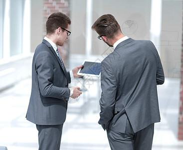 两位商务人士在数字平板电脑上阅读信息商务管理人员男性商业合伙男人会议生意人微笑触摸屏图片