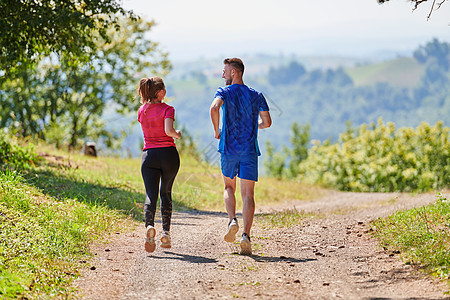 夫妻在乡村路上慢跑时享受健康的生活方式 在农村公路上游骑竞赛运动装太阳森林日落赛跑者男性女士公园晴天图片