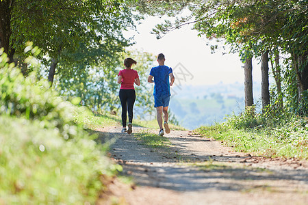 夫妻在乡村路上慢跑时享受健康的生活方式 在农村公路上游骑娱乐跑步赛跑者男性活动女性训练练习晴天竞赛图片