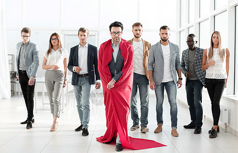 穿着超人斗篷的商务人士 带领一个犹豫不决的商业团队图片
