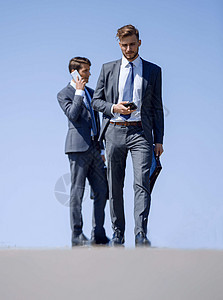 商业同事在街上站着时使用智能手机 也用智能手机图片
