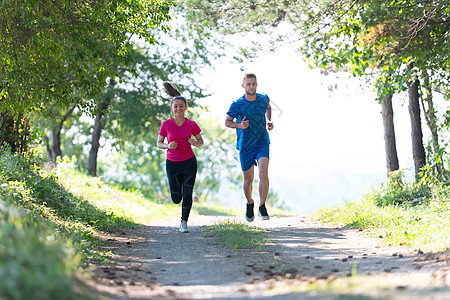 夫妻在乡村路上慢跑时享受健康的生活方式 在农村公路上游骑竞赛男性女性娱乐太阳公园日光晴天训练锻炼图片