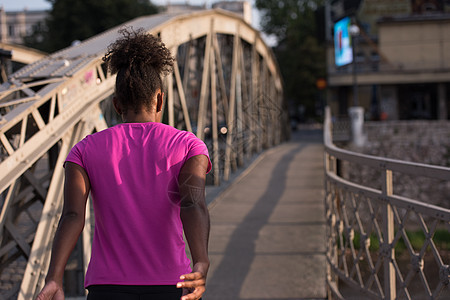 非洲裔美国妇女横跨大桥跑过跑步慢跑城市赛跑者女孩运动活力训练卷曲公园图片