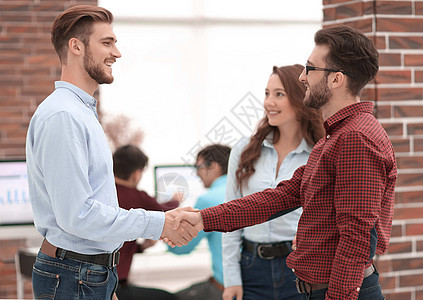 微笑的商务人士与当值同事握手相提并论工作男人联盟合伙力量商业工人会议公司律师图片