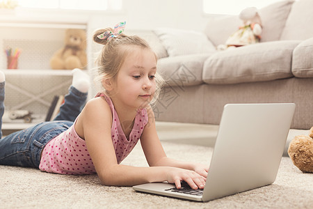 无聊的小女孩在笔记本电脑上做家庭作业女性游戏乐趣女孩学生互联网教育孩子技术耳机图片